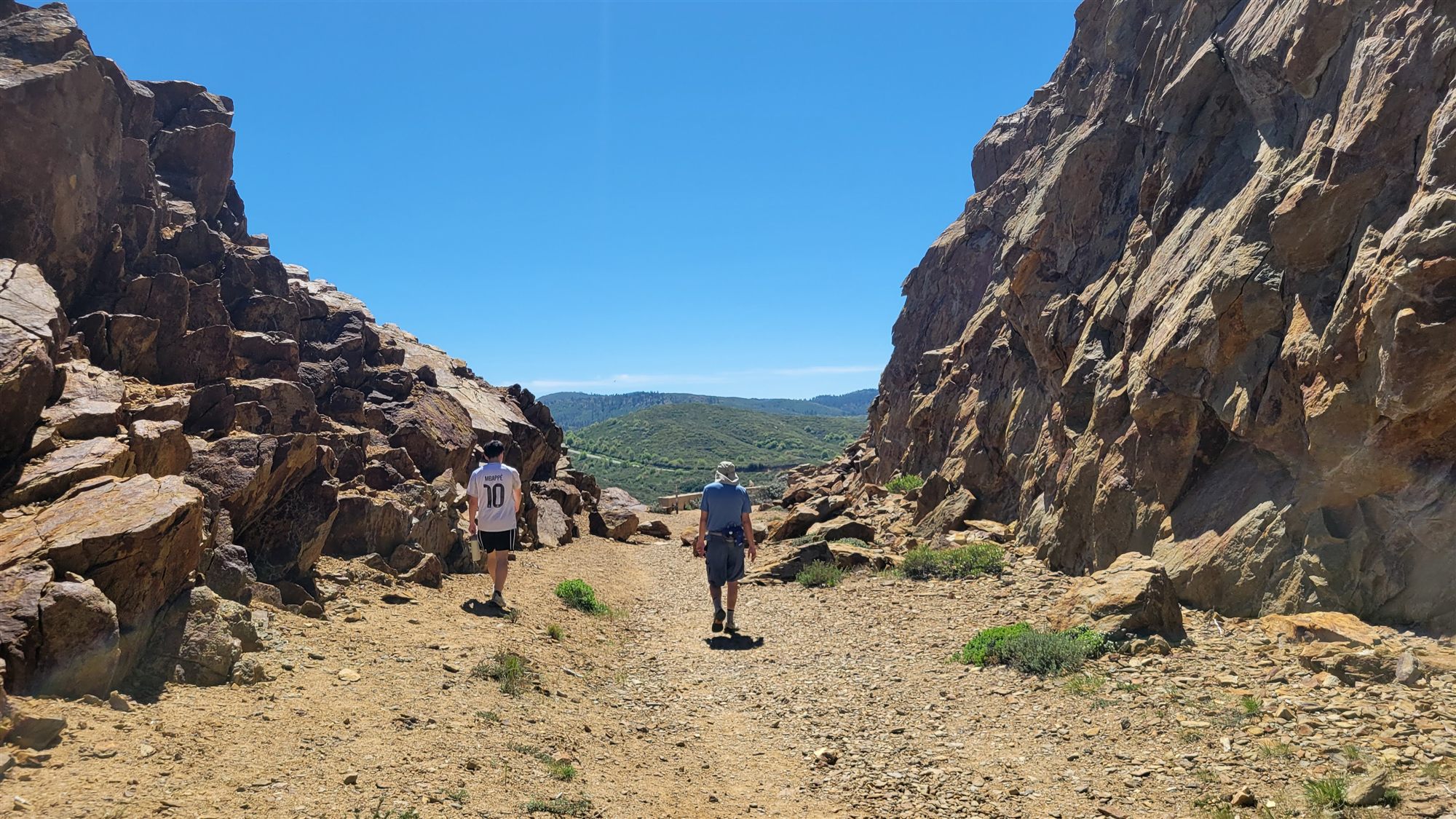 Two church members walking a rocky mountain trail on a sunny day