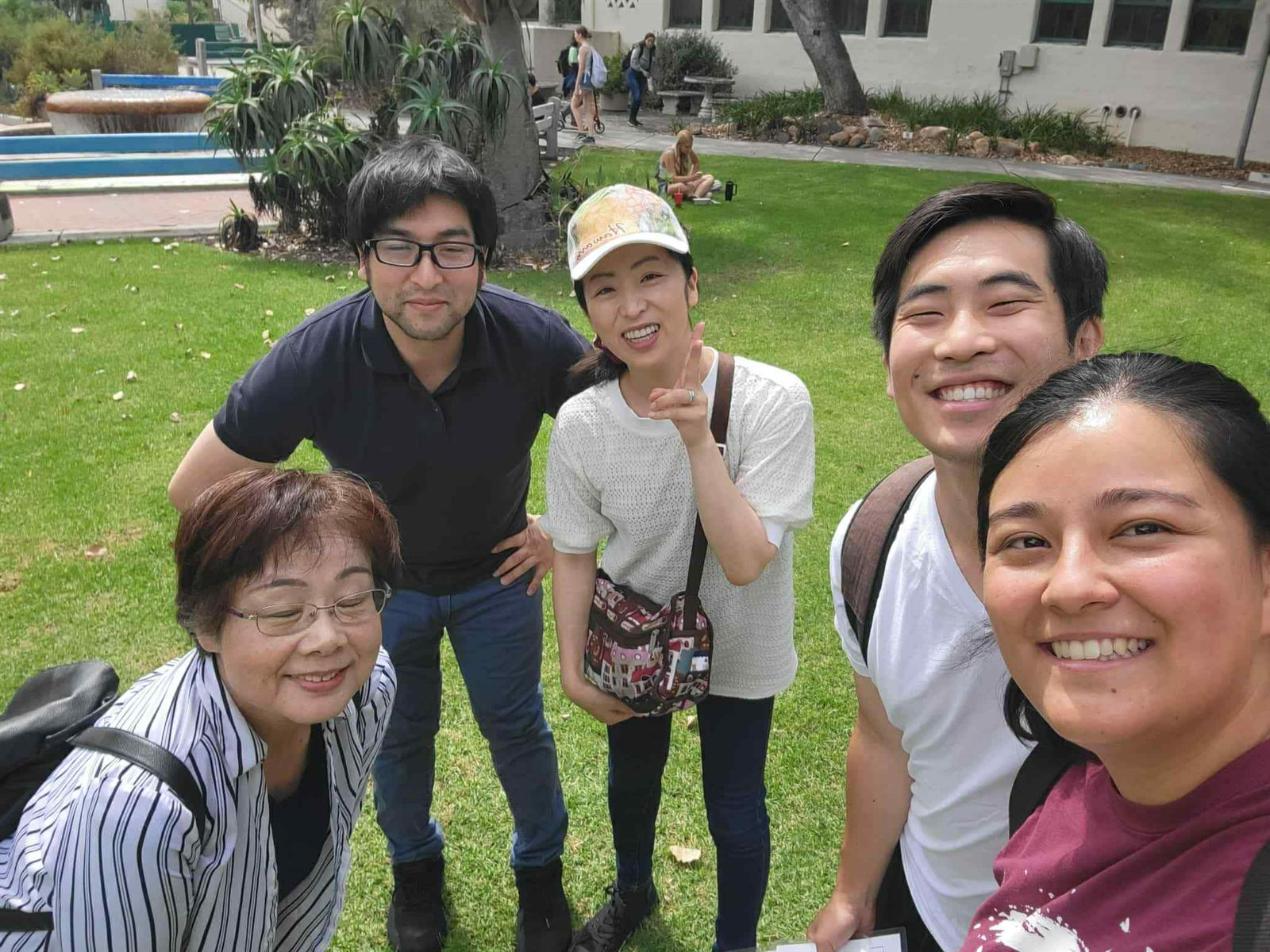 Five church members smiling for a selfie on a sunny lawn