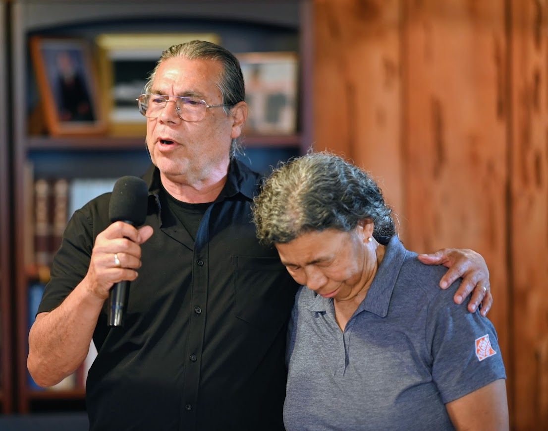 Assistant Pastor Walter Frank speaking into a microphone with his arm around a church member