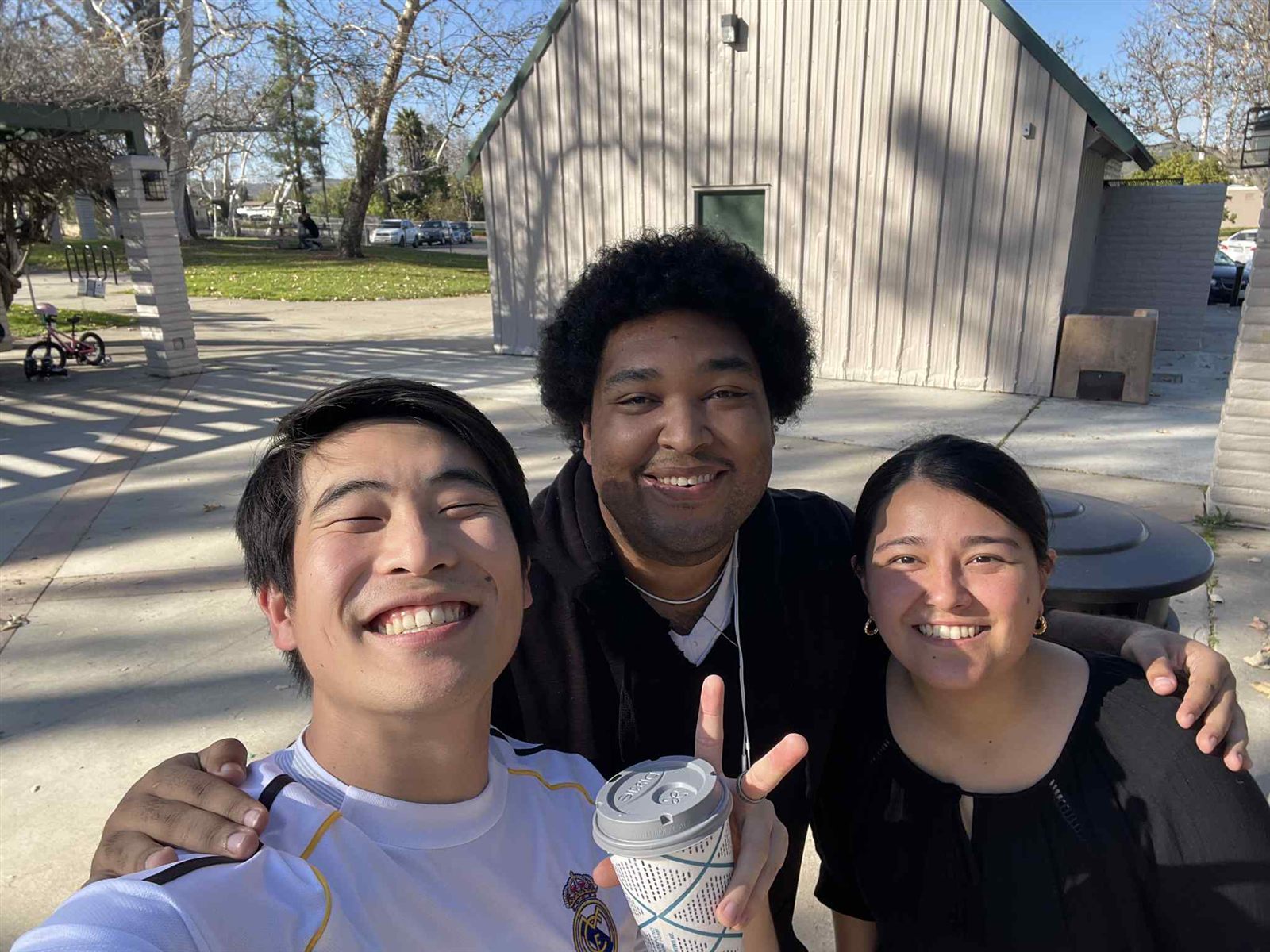 Three young adults from the church smiling for a selfie in a park