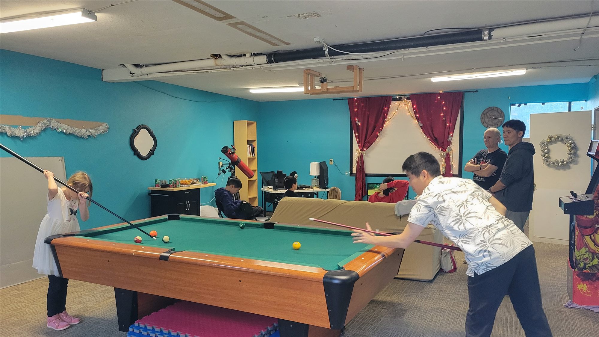 A father and daughter playing pool in the church youth room
